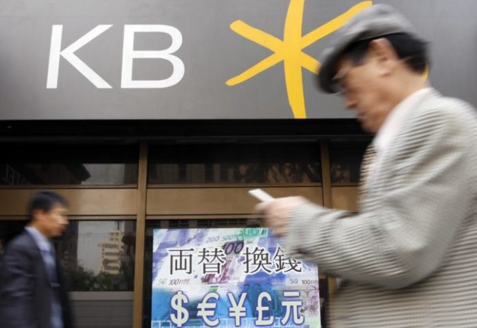 People walk past a branch of Kookmin bank in Seoul